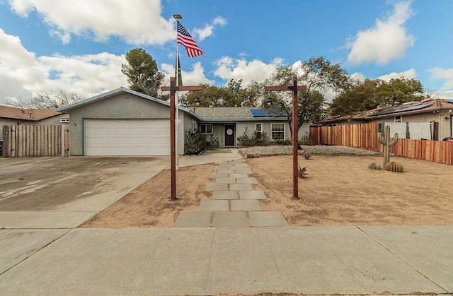 single story home featuring a garage, solar panels, concrete driveway, fence, and stucco siding