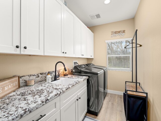40023 Woodsong Way, Oakhurst, CA 93644 - clothes washing area with cabinet space, light wood finished floors, visible vents, washer and clothes dryer, and a sink