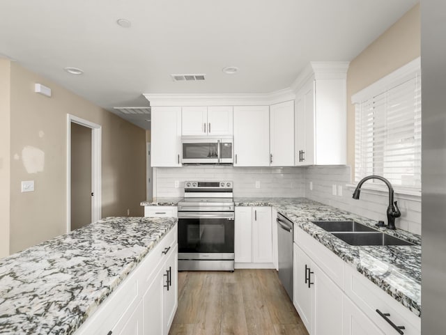 40023 Woodsong Way, Oakhurst, CA 93644 - kitchen with stainless steel appliances, a sink, visible vents, light wood-style floors, and backsplash