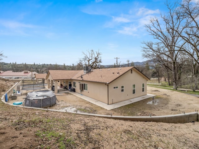 40023 Woodsong Way, Oakhurst, CA 93644 - rear view of house with a patio area, roof with shingles, central AC, and stucco siding