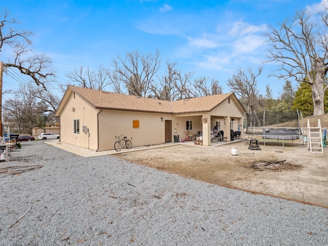 40023 Woodsong Way, Oakhurst, CA 93644 - view of front of home with gravel driveway, a patio area, a trampoline, and stucco siding