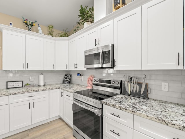 40023 Woodsong Way, Oakhurst, CA 93644 - kitchen with appliances with stainless steel finishes, white cabinets, light wood-style flooring, and tasteful backsplash