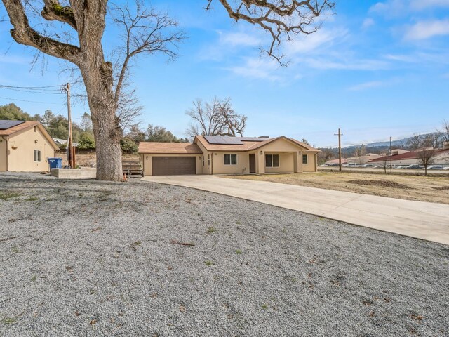40023 Woodsong Way, Oakhurst, CA 93644 - view of front of property featuring a garage, driveway, roof mounted solar panels, and stucco siding