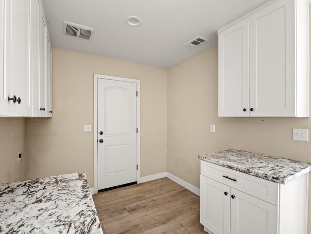40023 Woodsong Way, Oakhurst, CA 93644 - kitchen with light wood finished floors, white cabinetry, visible vents, and baseboards