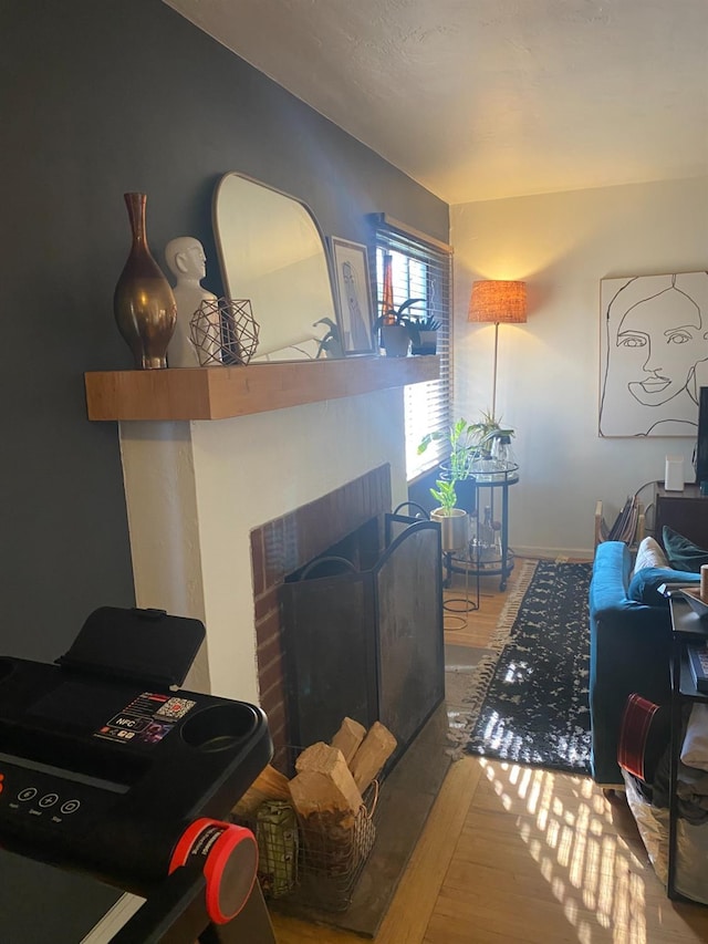 living area featuring a fireplace, wood finished floors, and baseboards