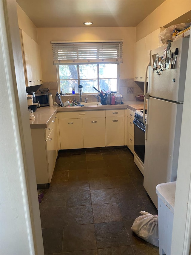 kitchen featuring a sink, light countertops, white appliances, and backsplash