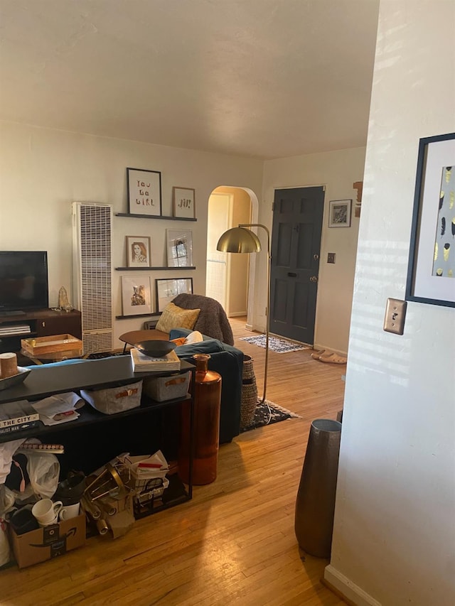 living area featuring arched walkways, baseboards, and light wood-style floors