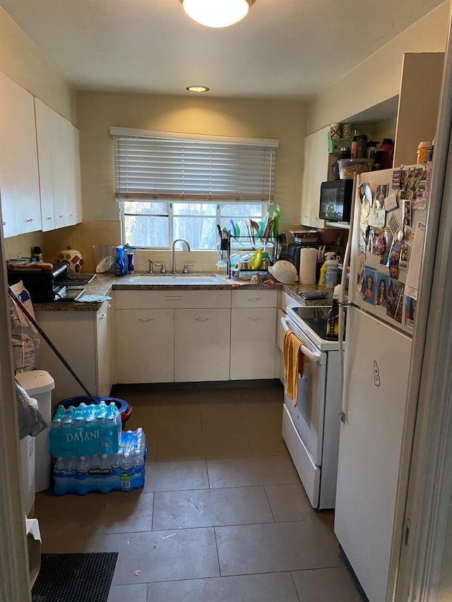 kitchen featuring tile patterned flooring, white appliances, white cabinets, and a sink