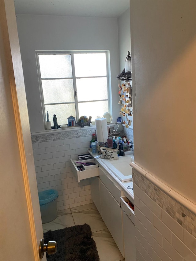 bathroom featuring a wainscoted wall, marble finish floor, tile walls, and vanity