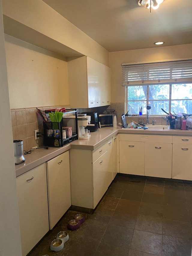 kitchen featuring light countertops, backsplash, and white cabinetry