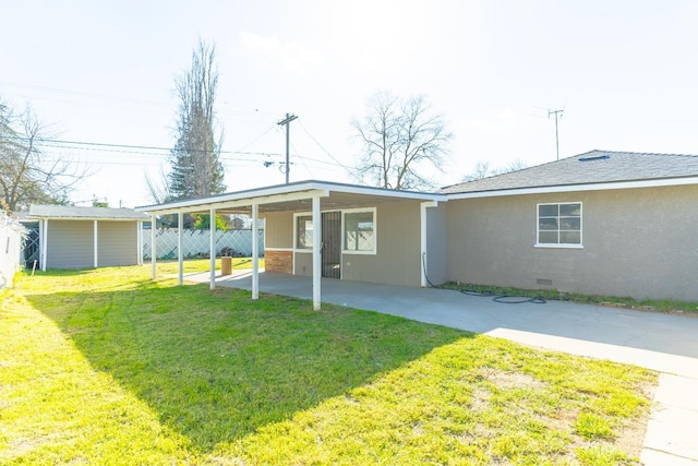 rear view of property featuring fence, roof with shingles, crawl space, a lawn, and stucco siding