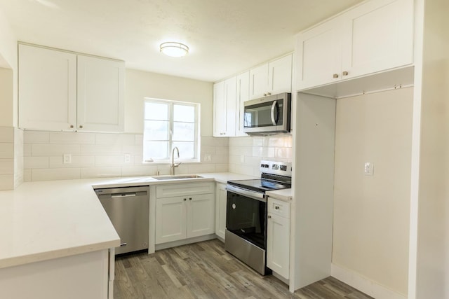 kitchen featuring backsplash, light wood-style flooring, appliances with stainless steel finishes, white cabinetry, and a sink