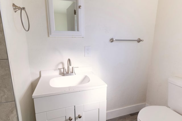 bathroom with toilet, baseboards, wood finished floors, and vanity