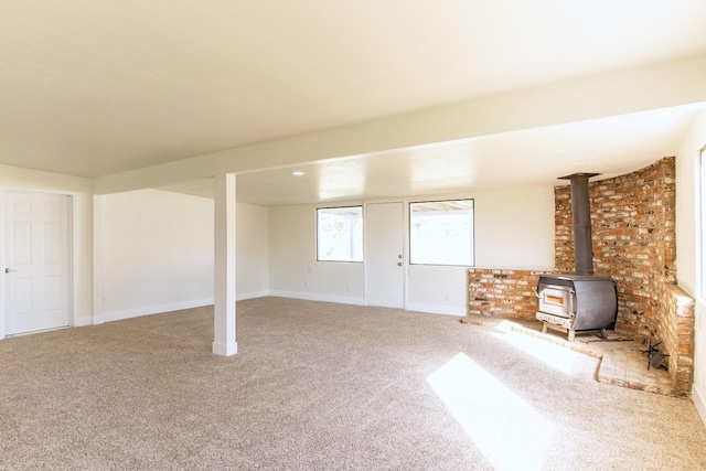 basement with a wood stove, carpet flooring, and baseboards