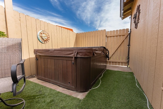 view of yard featuring a gate, fence, and a hot tub