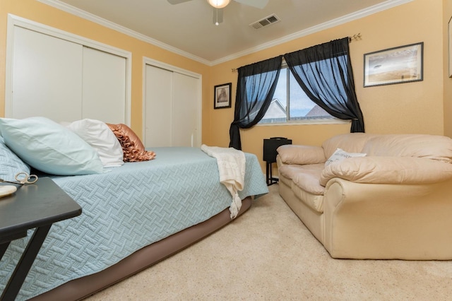 bedroom with ceiling fan, two closets, visible vents, and crown molding