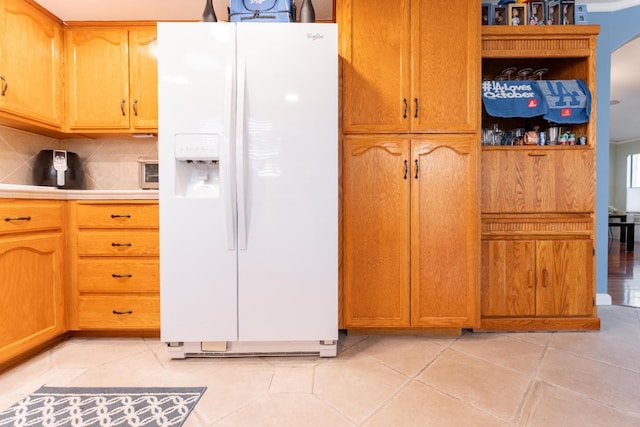 kitchen featuring white fridge with ice dispenser, light countertops, backsplash, and light tile patterned floors