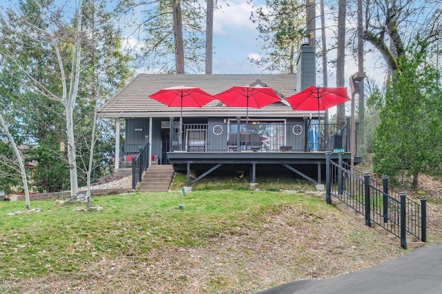 view of front of house featuring a chimney, stairs, and a front yard