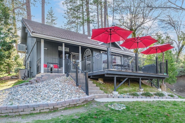 view of front of home featuring a deck, a shingled roof, stairs, and a front lawn