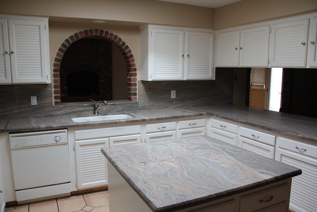 kitchen featuring dishwasher, a sink, white cabinets, and decorative backsplash