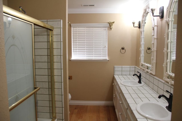 bathroom featuring wood finished floors, a sink, visible vents, and a shower stall