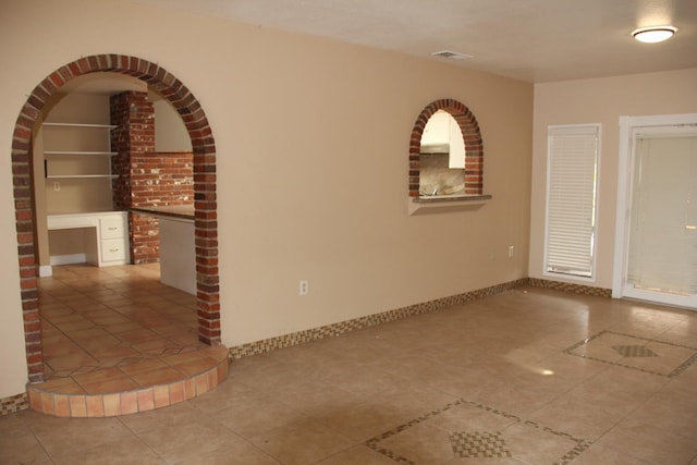 spare room with built in features, baseboards, visible vents, built in study area, and tile patterned floors