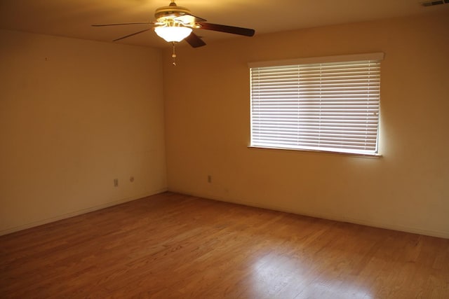 spare room featuring ceiling fan, wood finished floors, visible vents, and baseboards