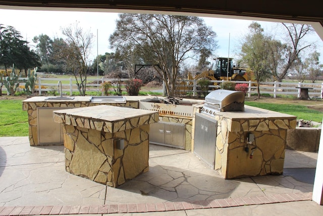 view of patio featuring a sink, exterior kitchen, and fence