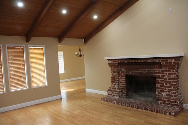 unfurnished living room featuring vaulted ceiling with beams, a fireplace, baseboards, and wood finished floors