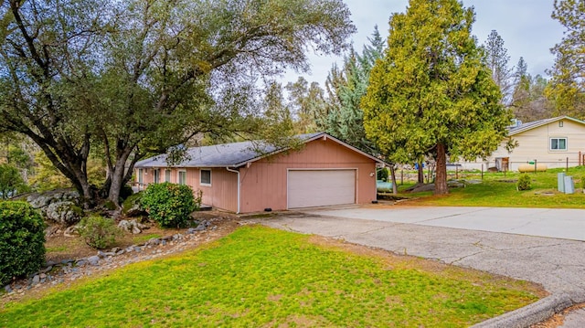 ranch-style home with a garage, a front lawn, fence, and aphalt driveway