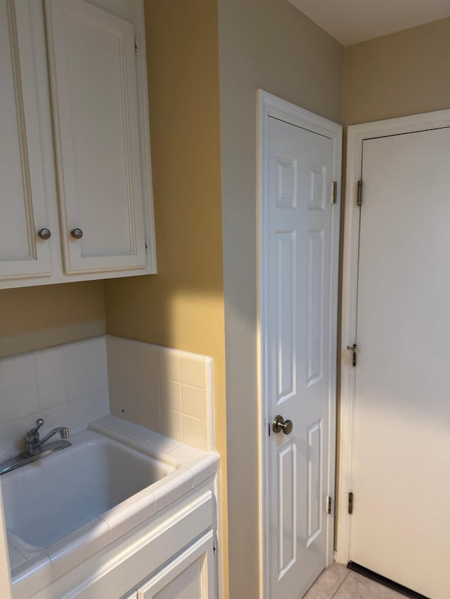 laundry room featuring light tile patterned flooring and a sink