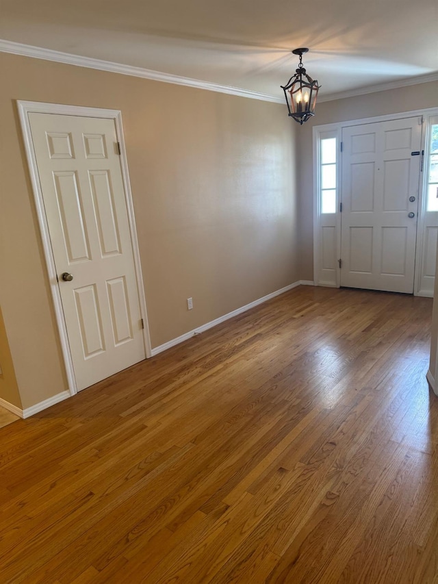 foyer featuring ornamental molding, baseboards, an inviting chandelier, and wood finished floors