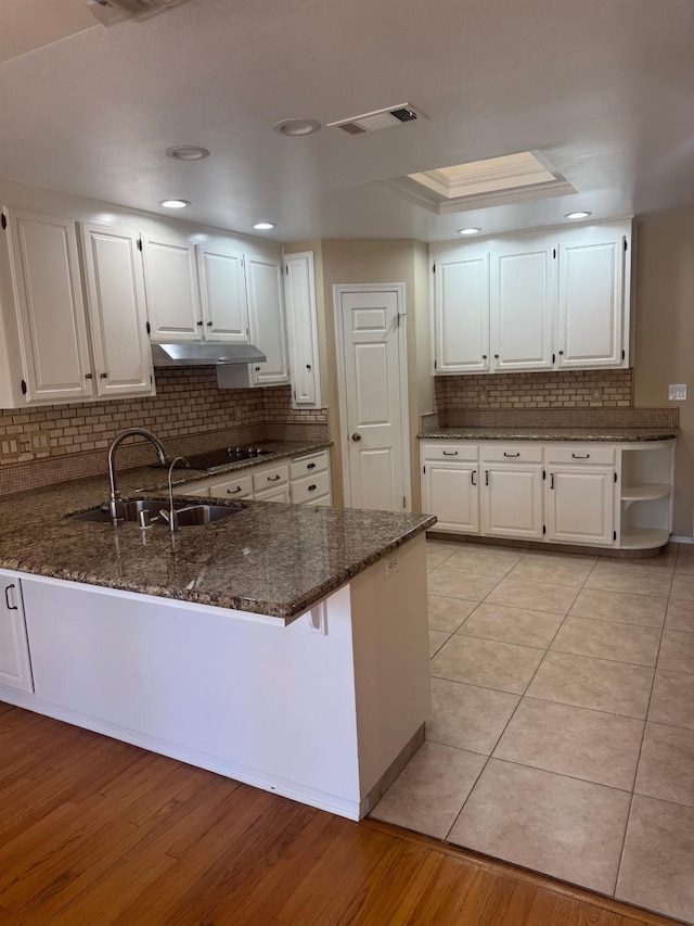 kitchen featuring a peninsula, under cabinet range hood, visible vents, and white cabinets