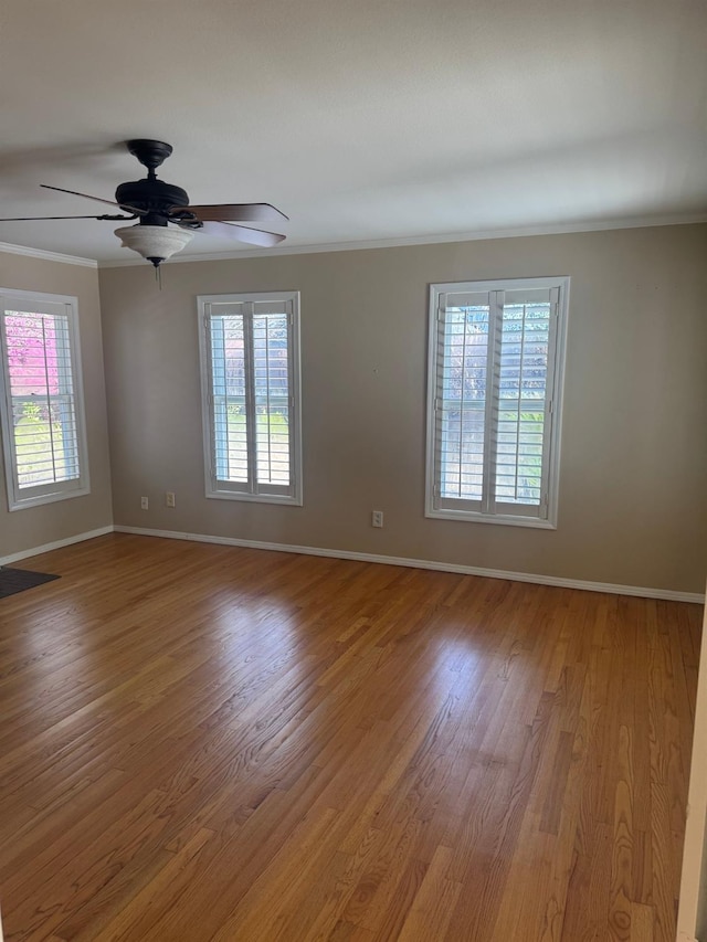 spare room featuring ceiling fan, crown molding, baseboards, and wood finished floors