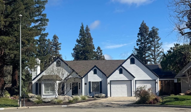 view of front facade with a garage, driveway, and a chimney