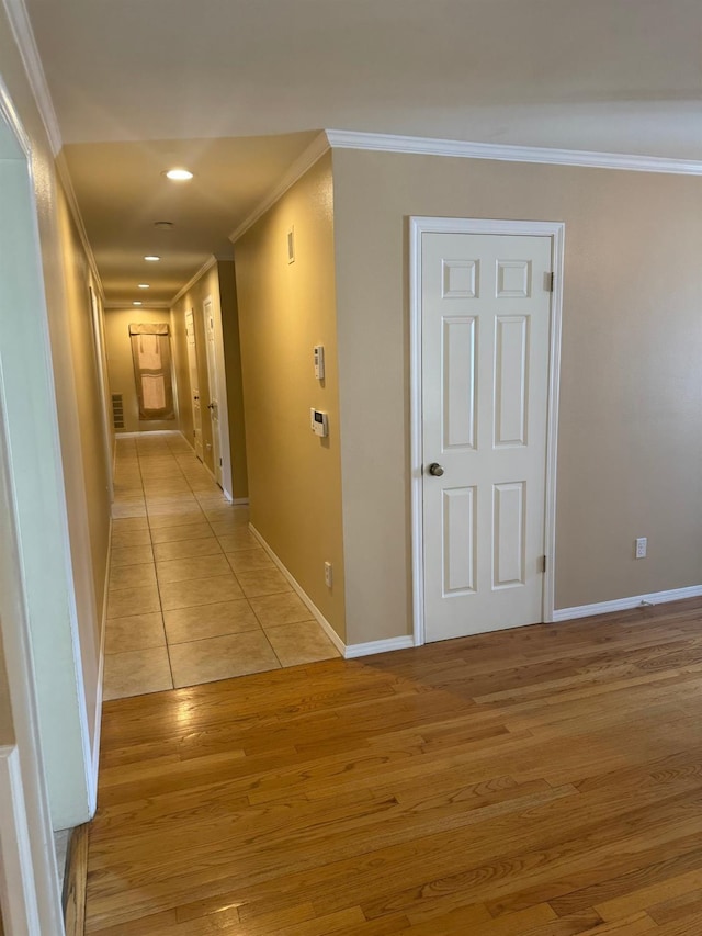 hallway with recessed lighting, crown molding, light wood-style flooring, and baseboards