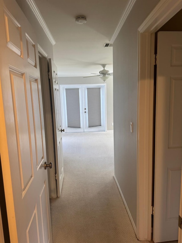 hallway with carpet, visible vents, baseboards, and crown molding