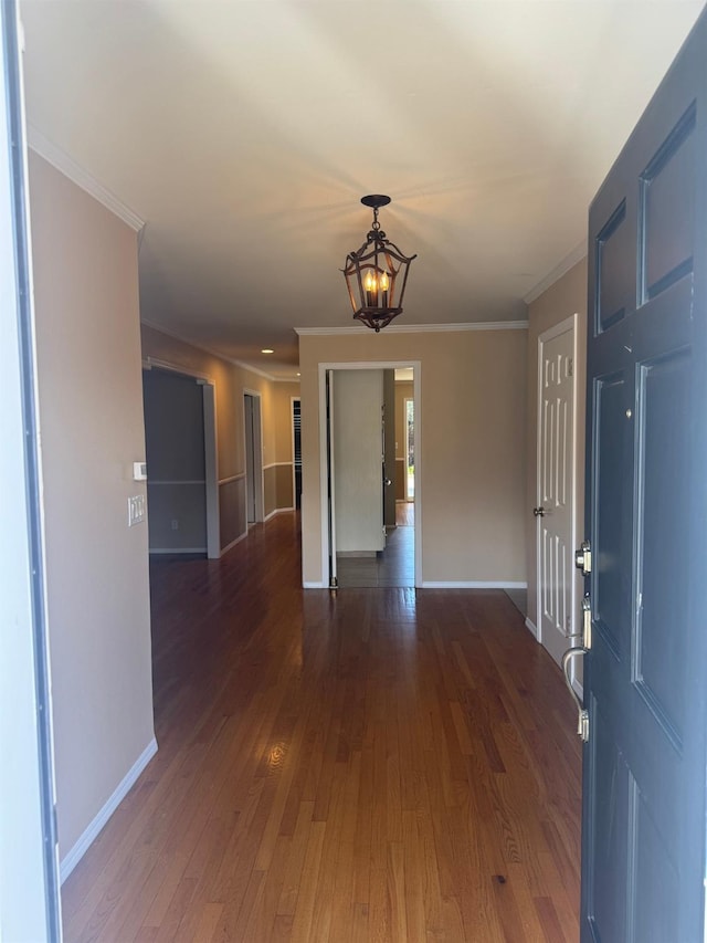 unfurnished room with crown molding, a notable chandelier, baseboards, and wood finished floors