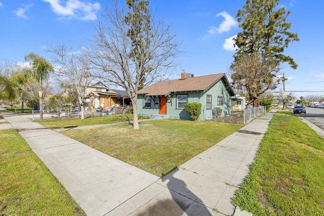 bungalow-style house with a front yard, fence, and a chimney