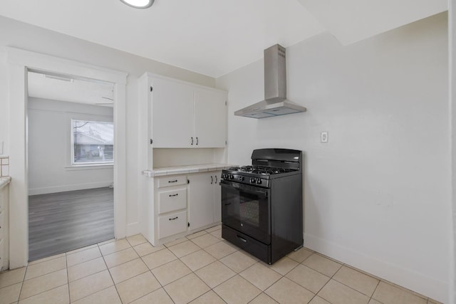 kitchen with tile counters, light tile patterned flooring, wall chimney exhaust hood, and black range with gas stovetop