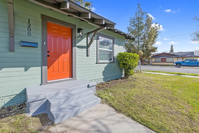 view of exterior entry featuring a lawn