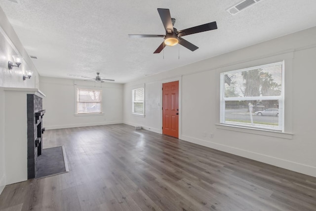 unfurnished living room featuring a textured ceiling, visible vents, and wood finished floors