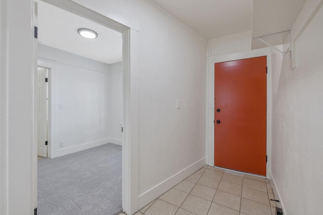 entryway featuring light carpet, baseboards, and light tile patterned flooring