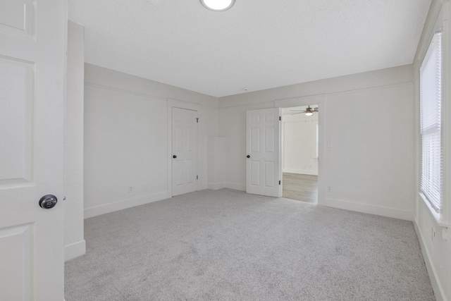 carpeted empty room featuring ceiling fan, a textured ceiling, and baseboards