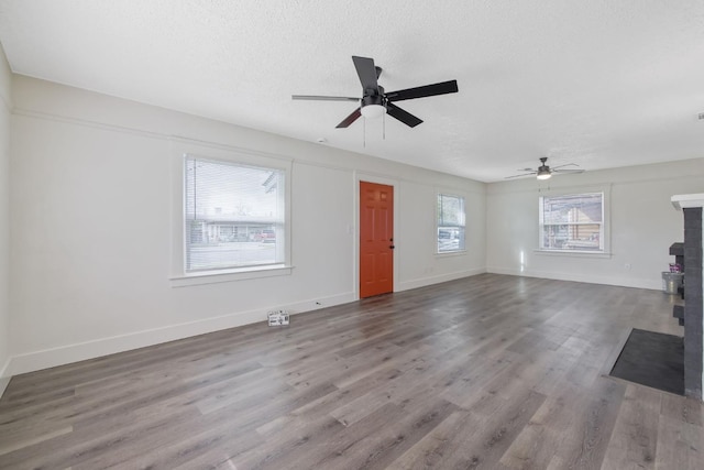 unfurnished living room featuring ceiling fan, a textured ceiling, baseboards, and wood finished floors