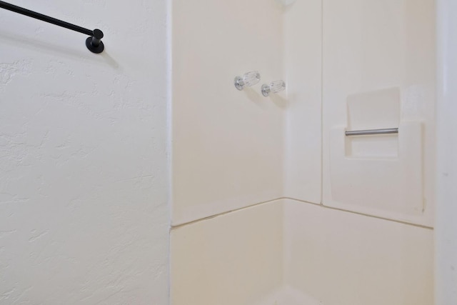 interior details with a shower and a textured wall