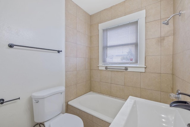 bathroom with toilet, tiled bath, and a sink