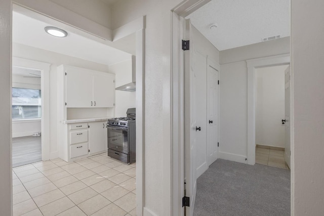 interior space with baseboards, light tile patterned flooring, visible vents, and light colored carpet