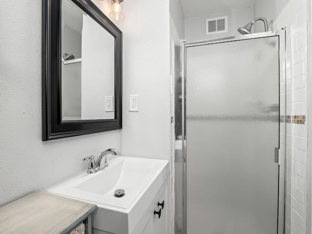 bathroom featuring vanity, visible vents, and a shower stall