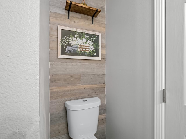 bathroom featuring wooden walls and toilet